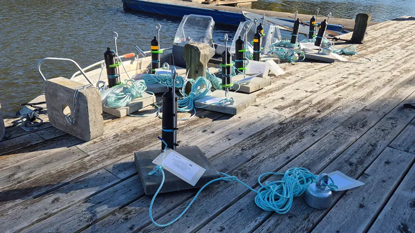 Svarta cylindriska instrument är monterade på tyngder och utlagda på en träbrygga.