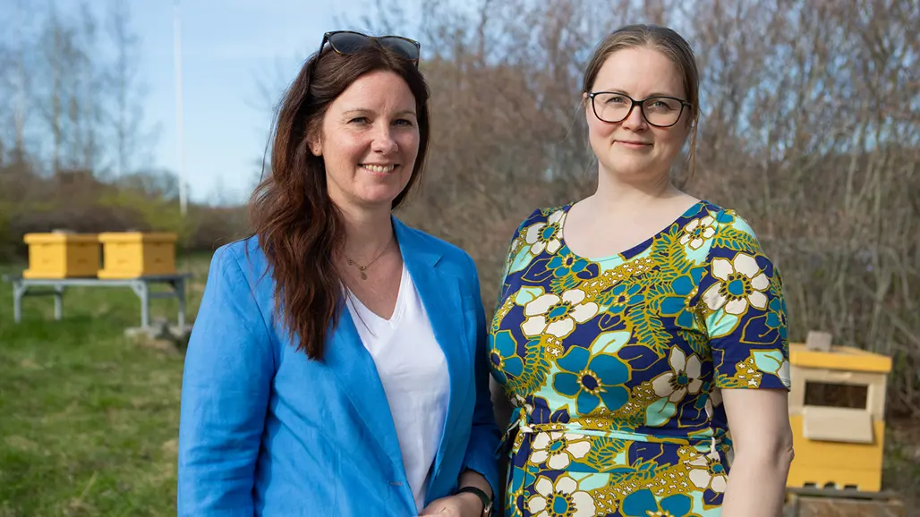 Två kvinnor framför bikupor.