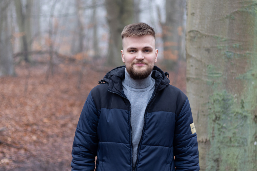 man i täckjacka i bokskog