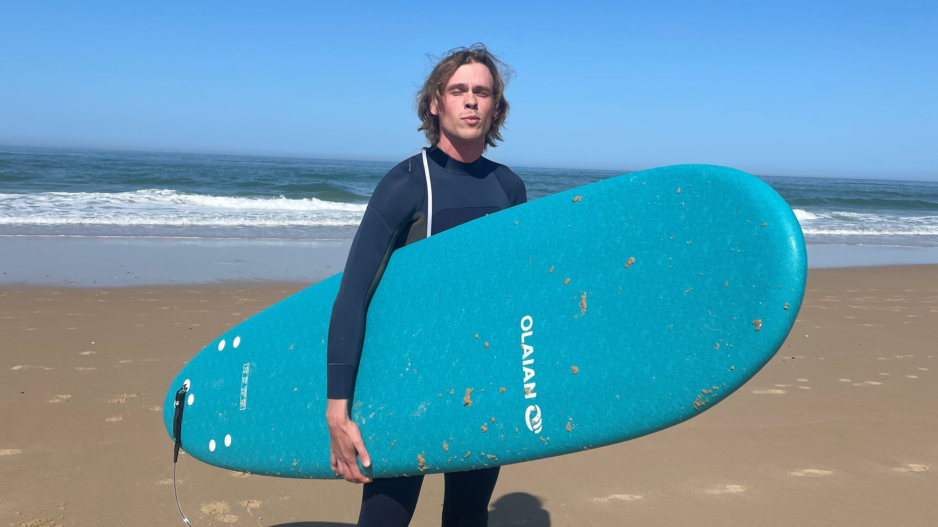 Johan with a surf board on a beach.