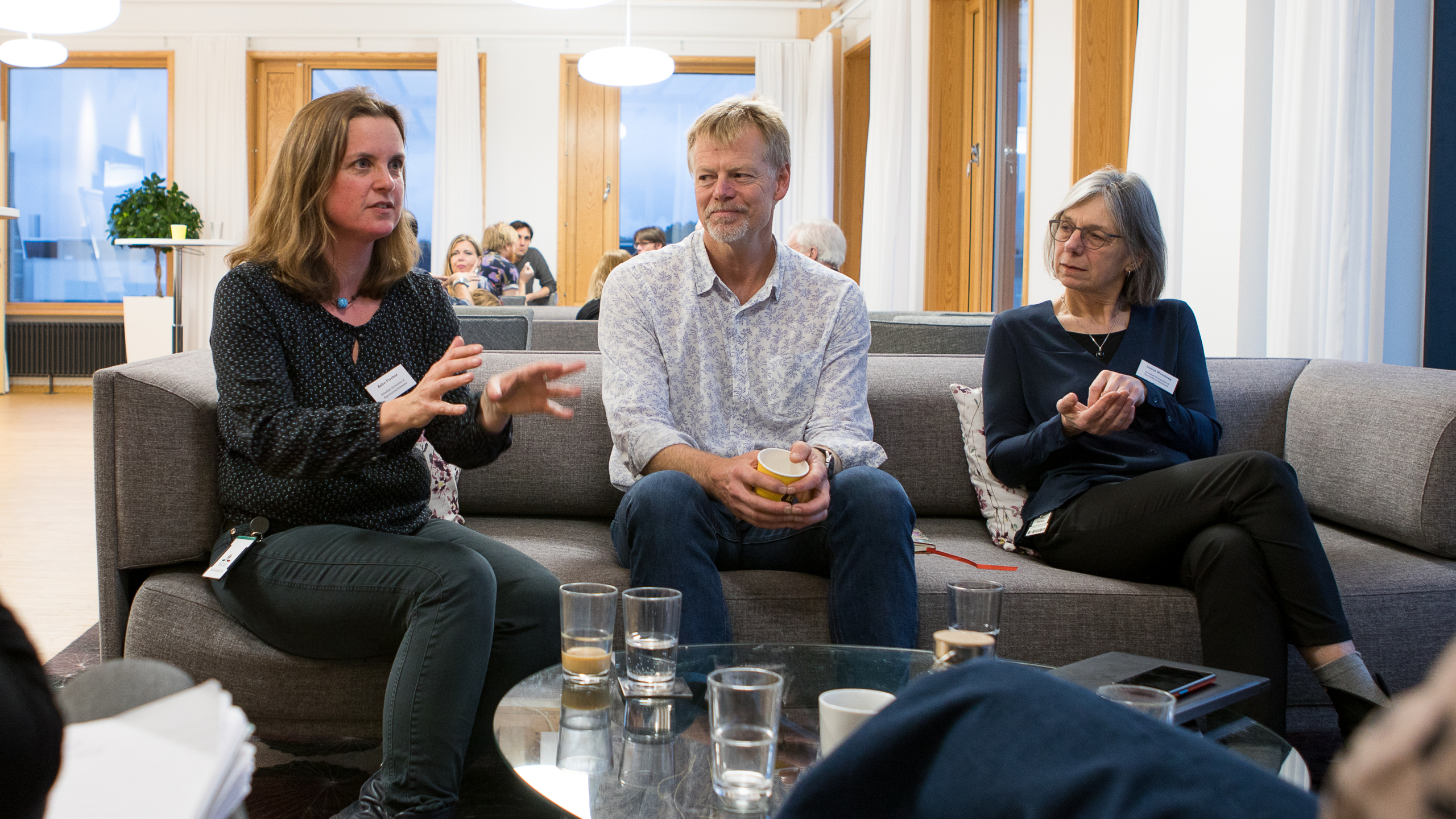 Tre personer i en soffa samtalar, foto.