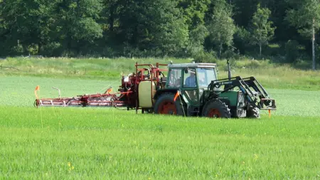 En traktor som applicerar bekämpningsmedel på en jordbruksåker