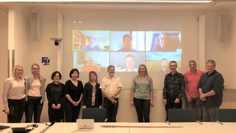 Group picture in front of a projector screen with even more participants.