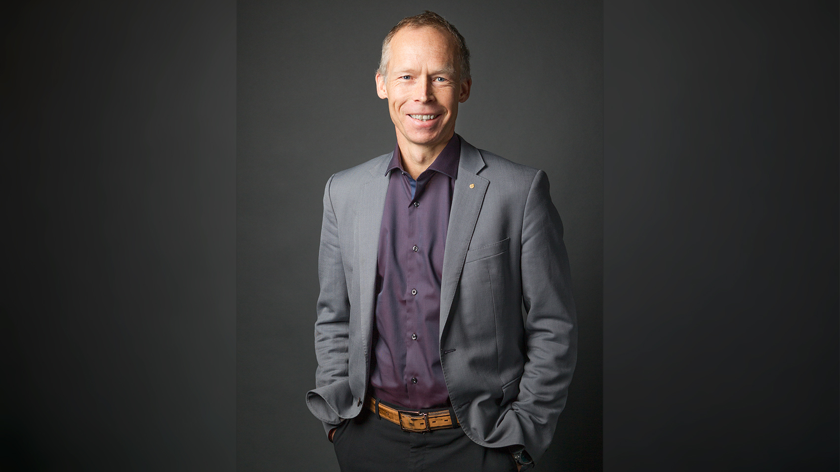 En person i grå kostym och vinröd skjorta.