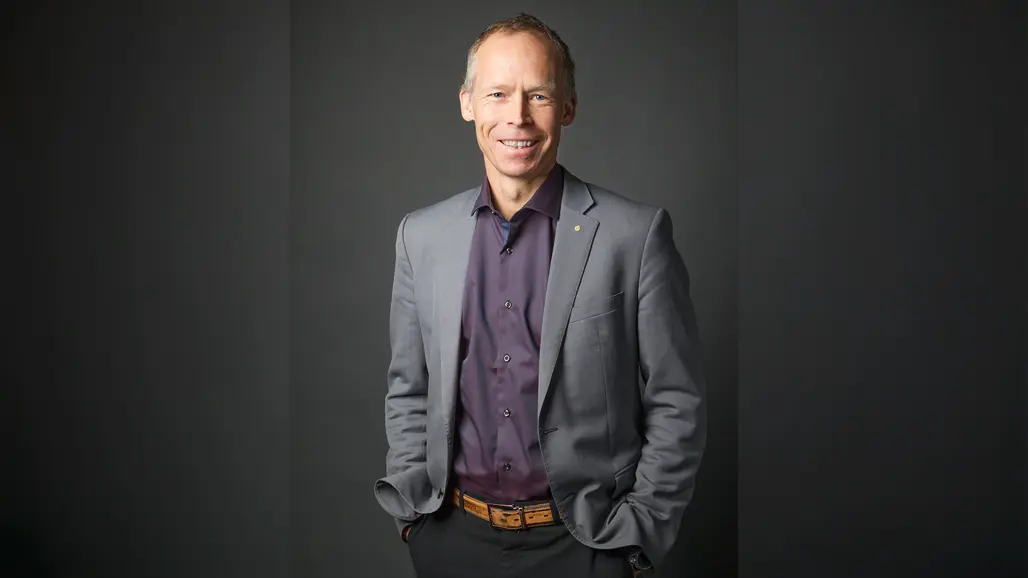 En person i grå kostym och vinröd skjorta.