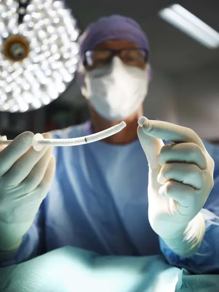 A person in surgical clothes holds up a product. Photo.