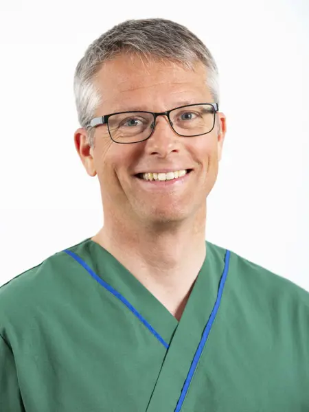 A portrait of a smiling man with glasses and a green shirt. Photo.