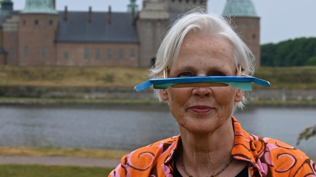 En kvinna bär glasögon med en utskjutande plastremsa som visualiserar stigande havsnivåer.