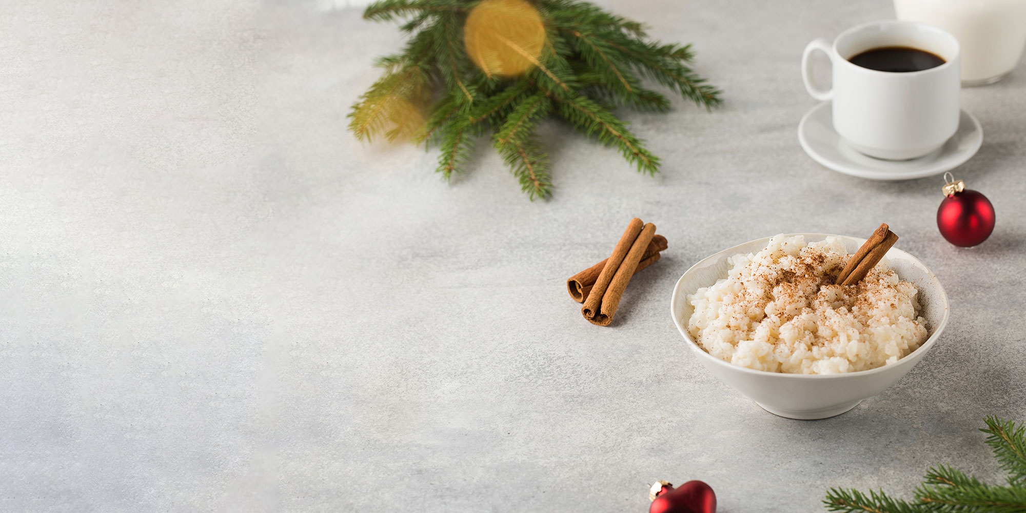 Traditionell svensk risgrynsgröt med kanel i en skål, omgivet av julpynt. Foto: Shutterstock.