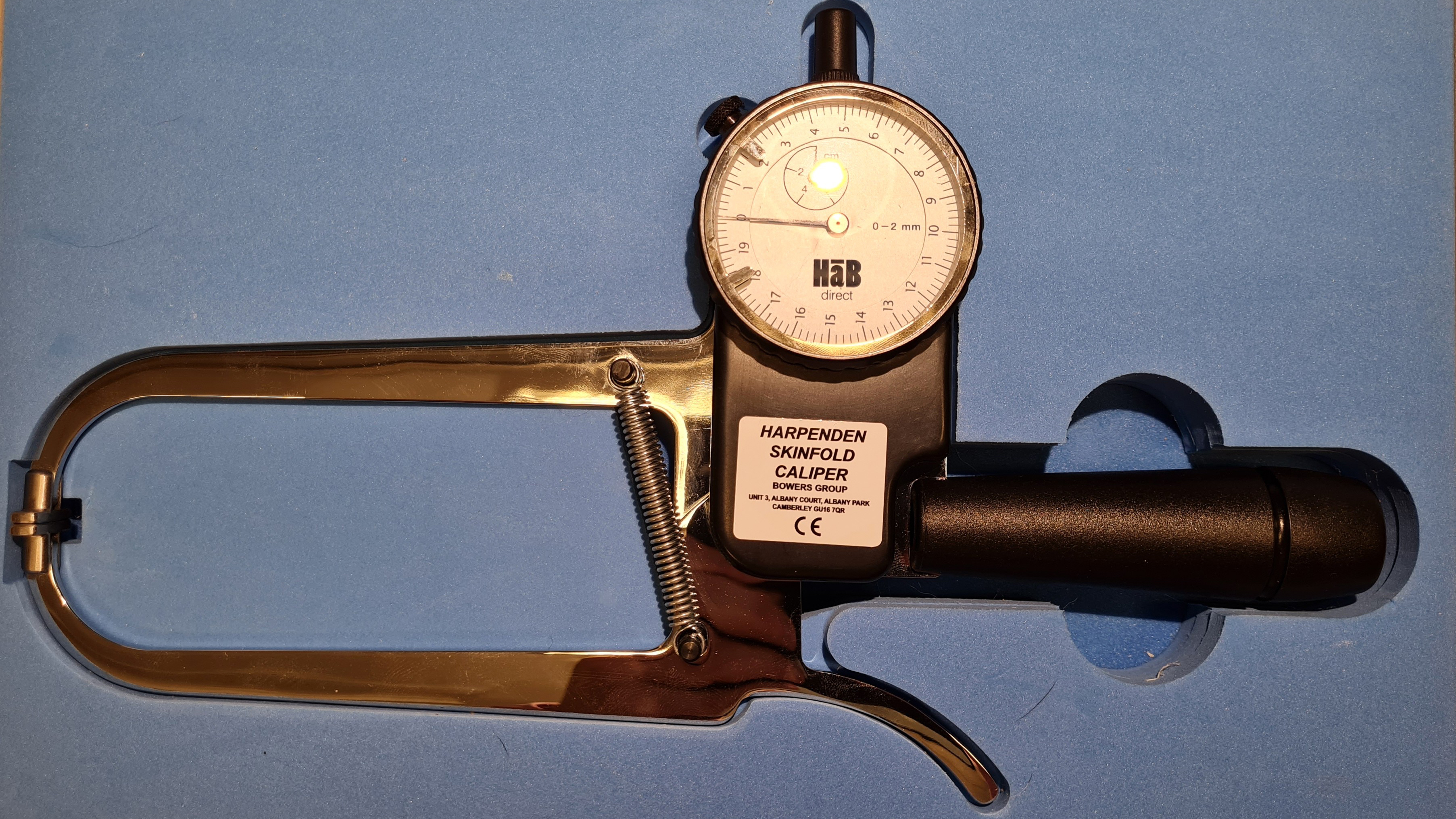 Ett tångliknande verktyg med en rund mätare och texten Harpenden Skinfold Caliper. Foto.