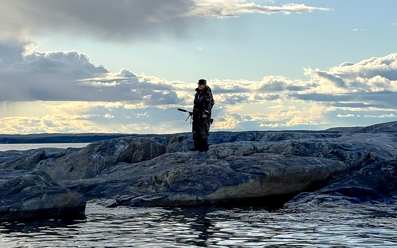 En jägare står på ett par klippor vid kusten
