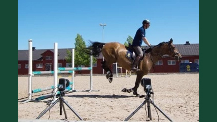 Foto av en häst med ryttare som landar efter ett hinder, filmat av uppställda kameror.