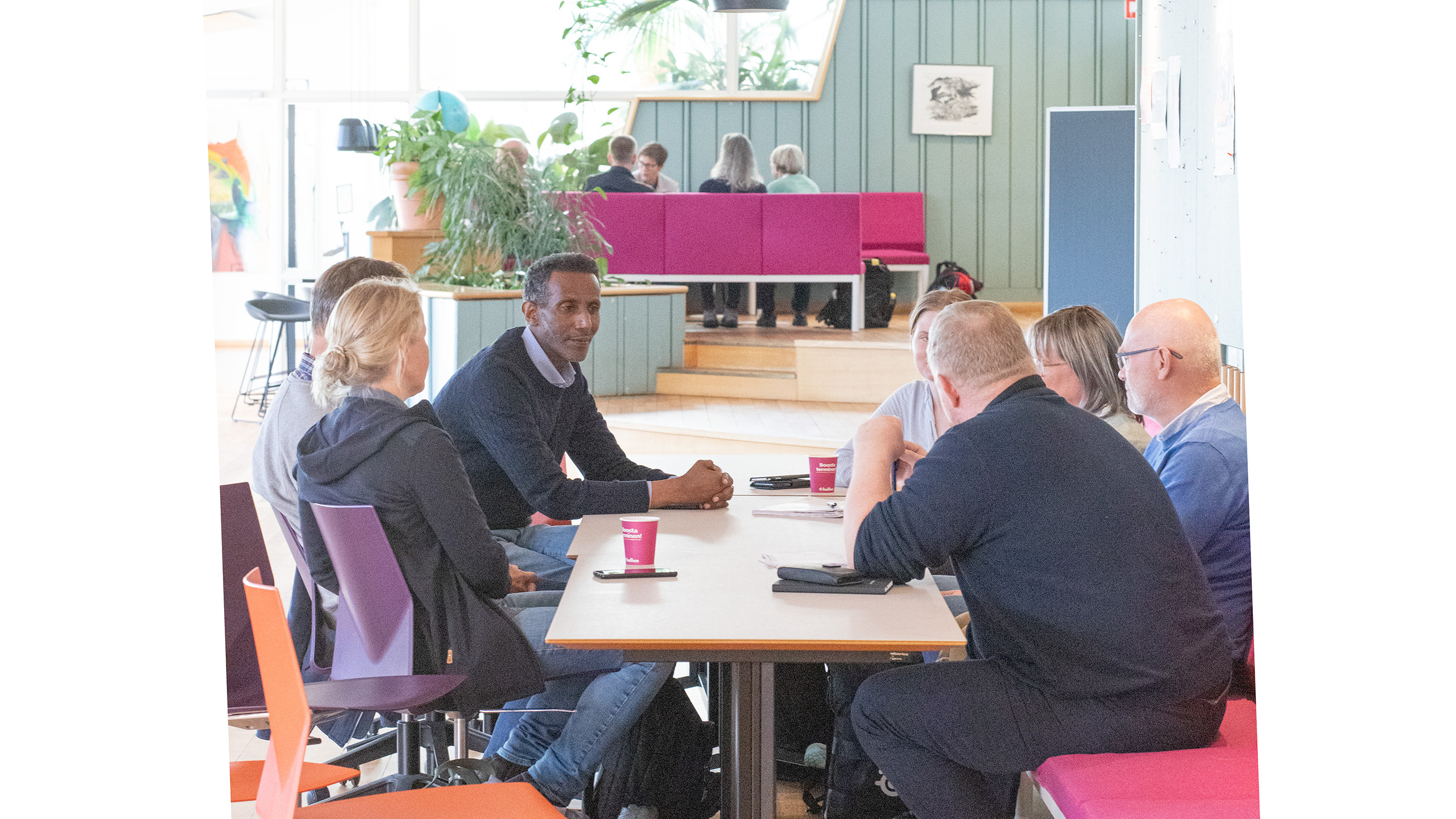 Tolv personer sitter i två grupper och pratar.