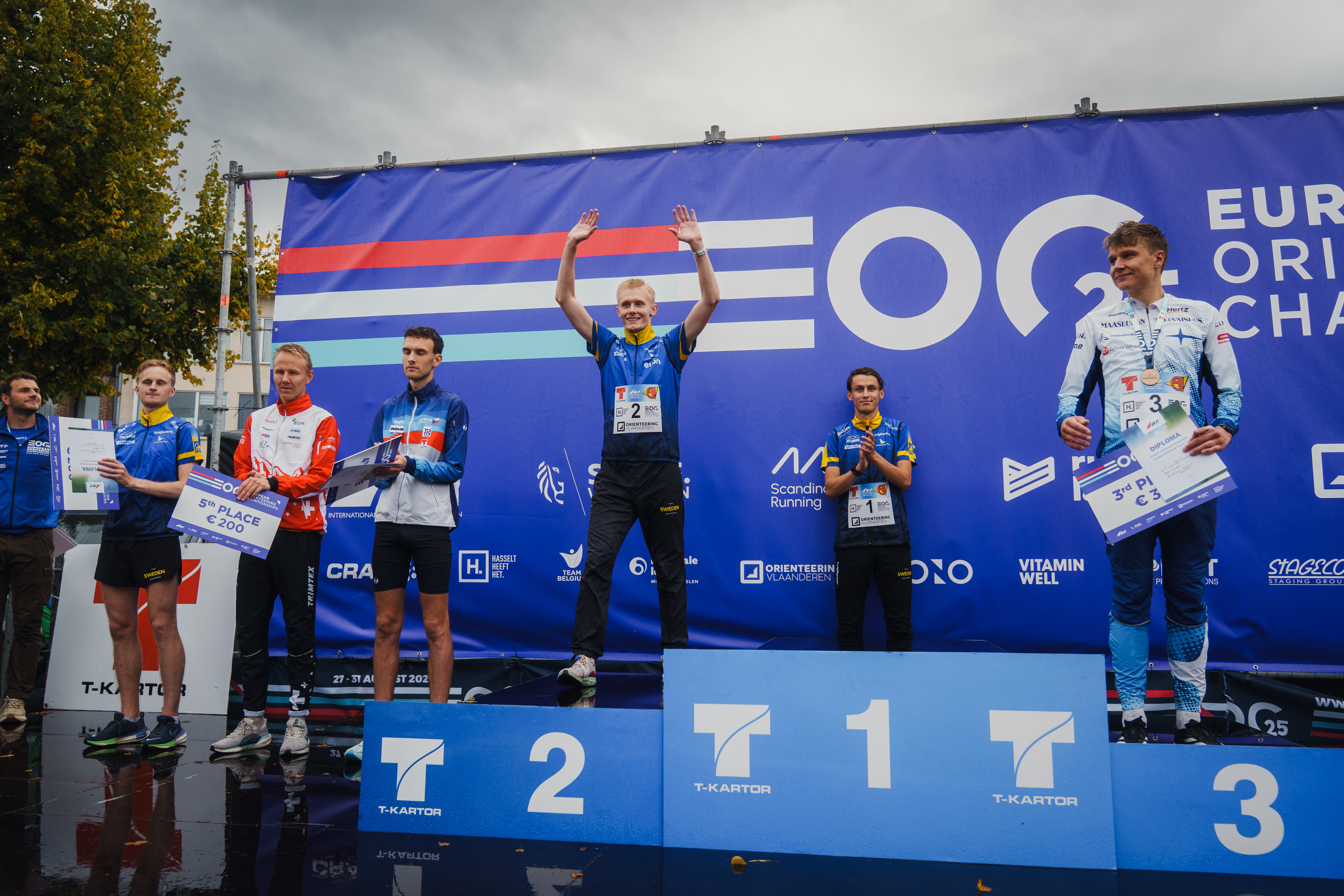 Prispall med ung man som sträcker händerna i luften. Foto.