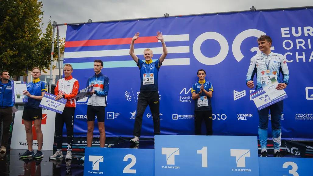 Prispall med ung man som sträcker händerna i luften. Foto.