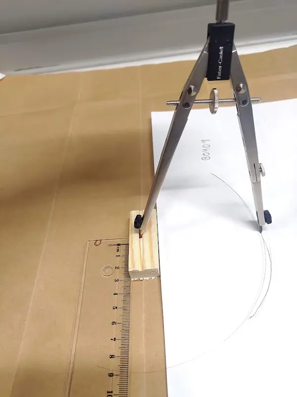 Passare ritar en kurva från en träbit på papper.