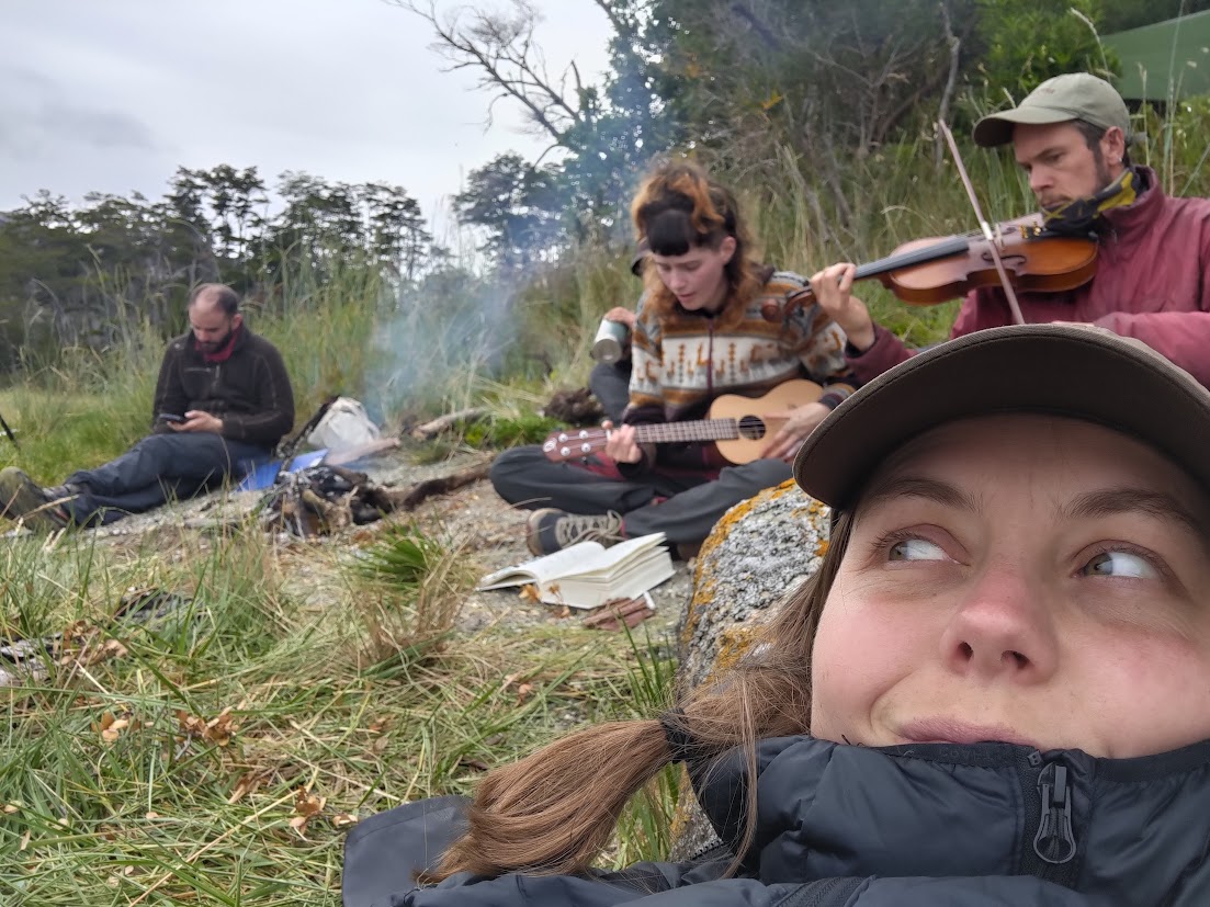 Person i förgrunden medan andra spelar instrument vid en lägereld.