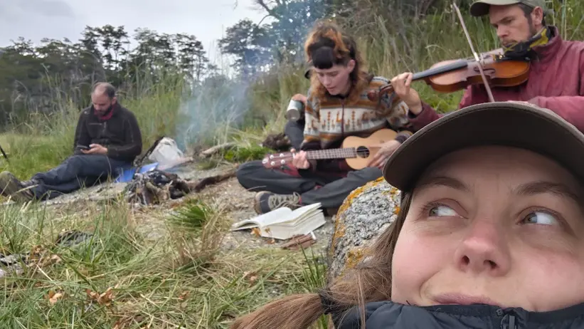 Person i förgrunden medan andra spelar instrument vid en lägereld.