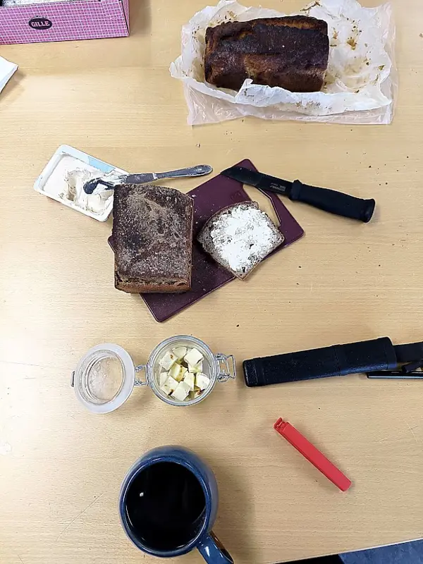 Bröd, smör och kaffe uppdukat på ett bord.