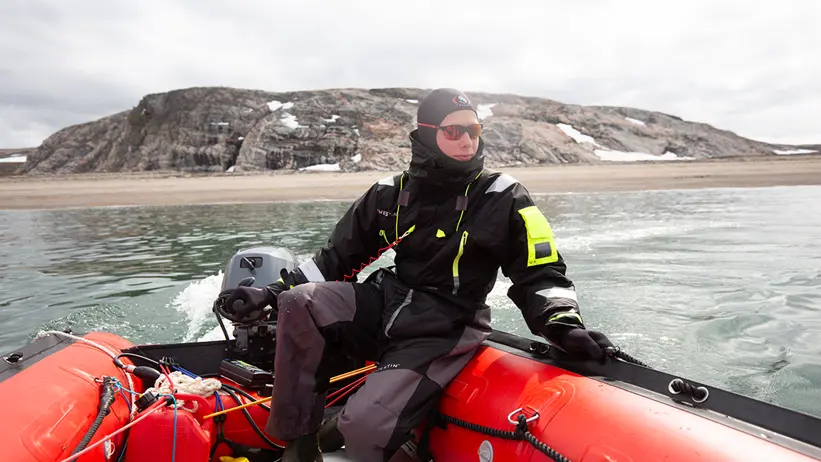Person i överlevnadsdräkt i en gummibåt