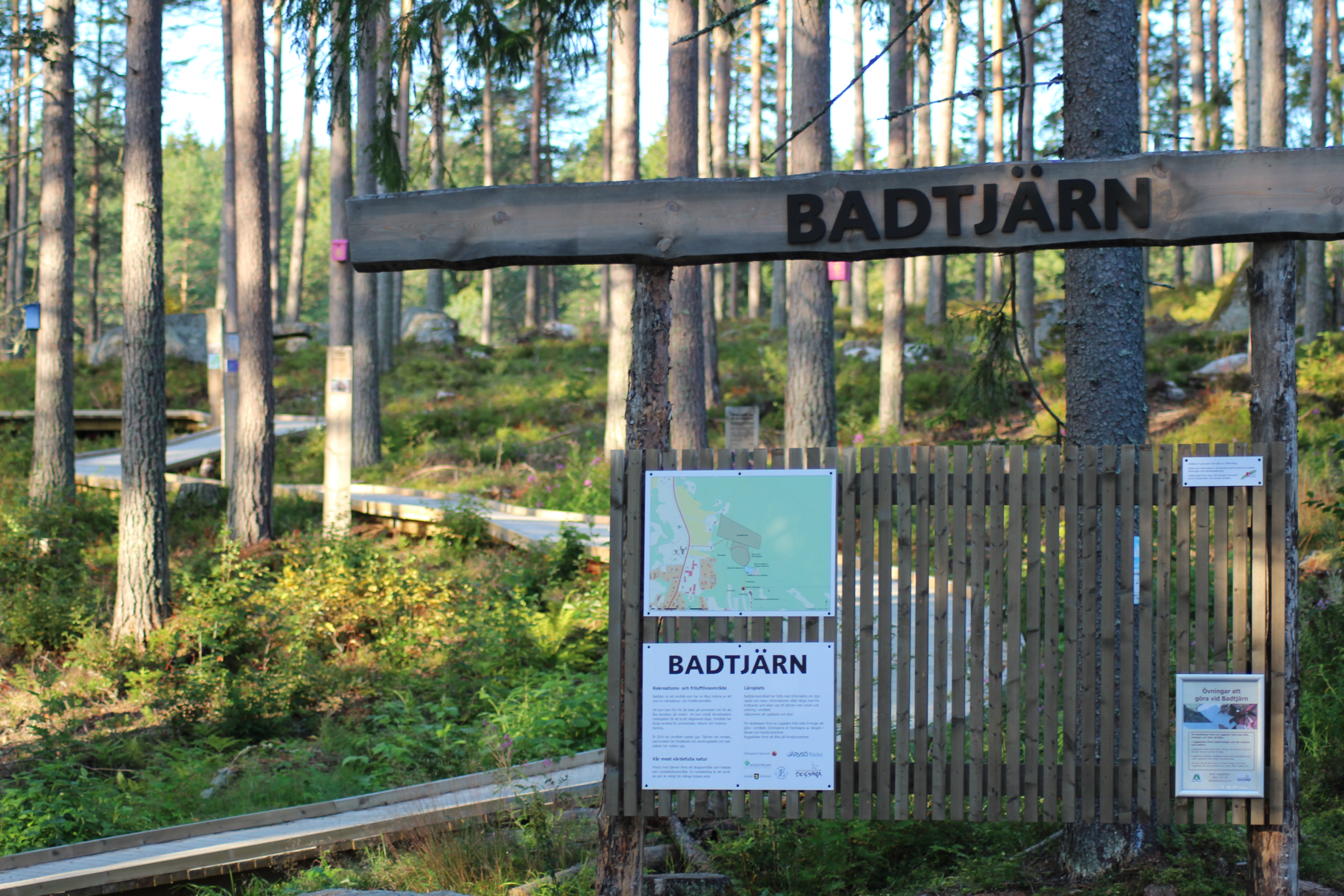 Ett skyltställ i skog med texten badtjärn
