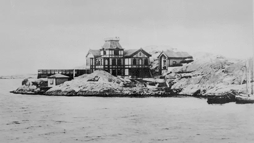 En vacker träbyggnad som ligger på ett par klippor vid havet.