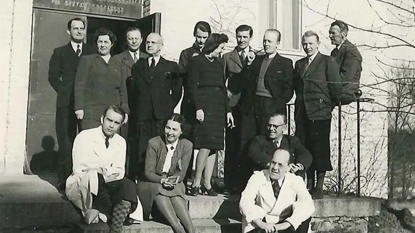 Flera personer iklädda finkläder och labbrockar står på en trappa.