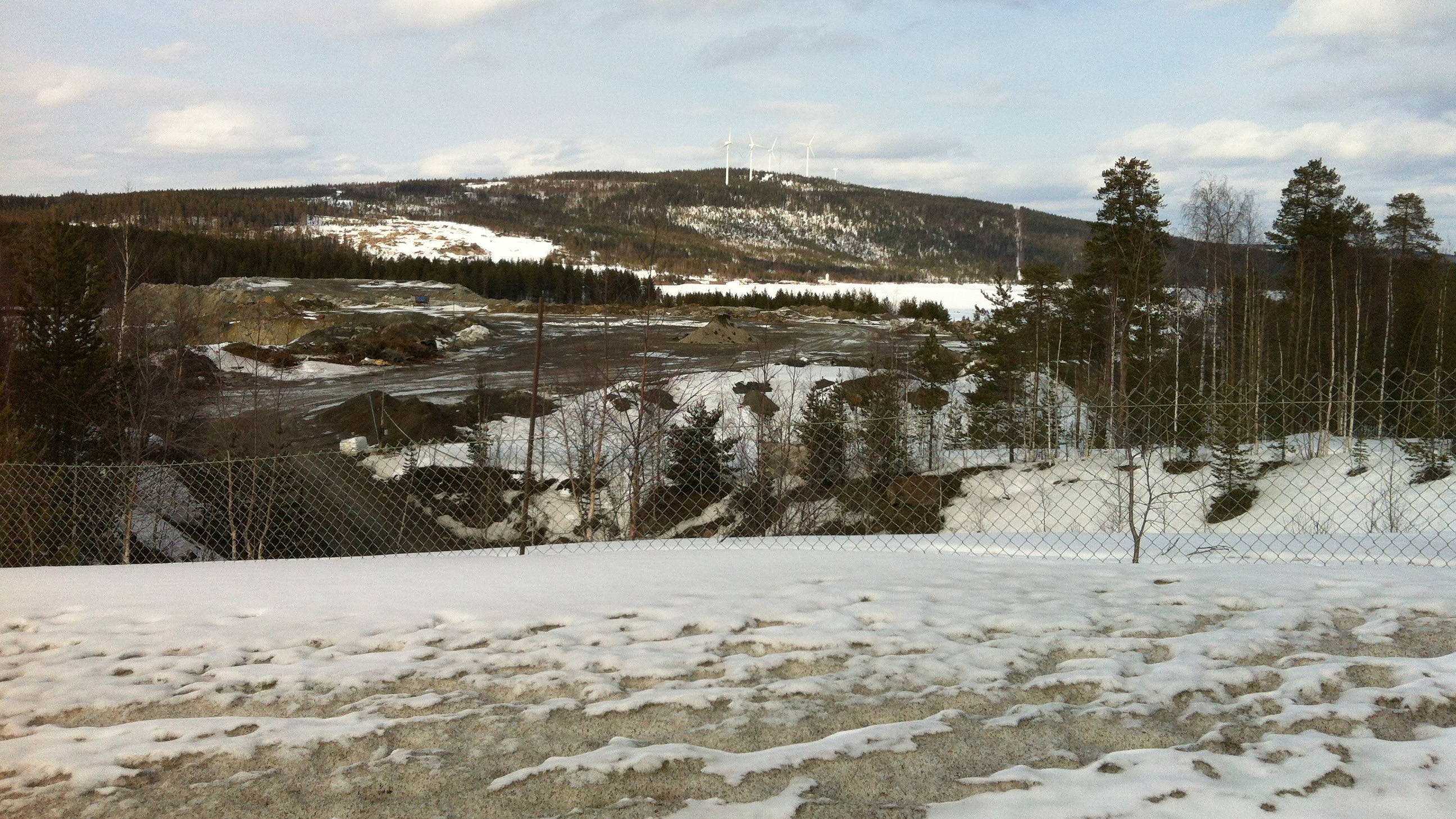 Vintrig landskapsbild med en kulle med några vindkraftverk på långt avstånd. Foto: Anna Skarin.