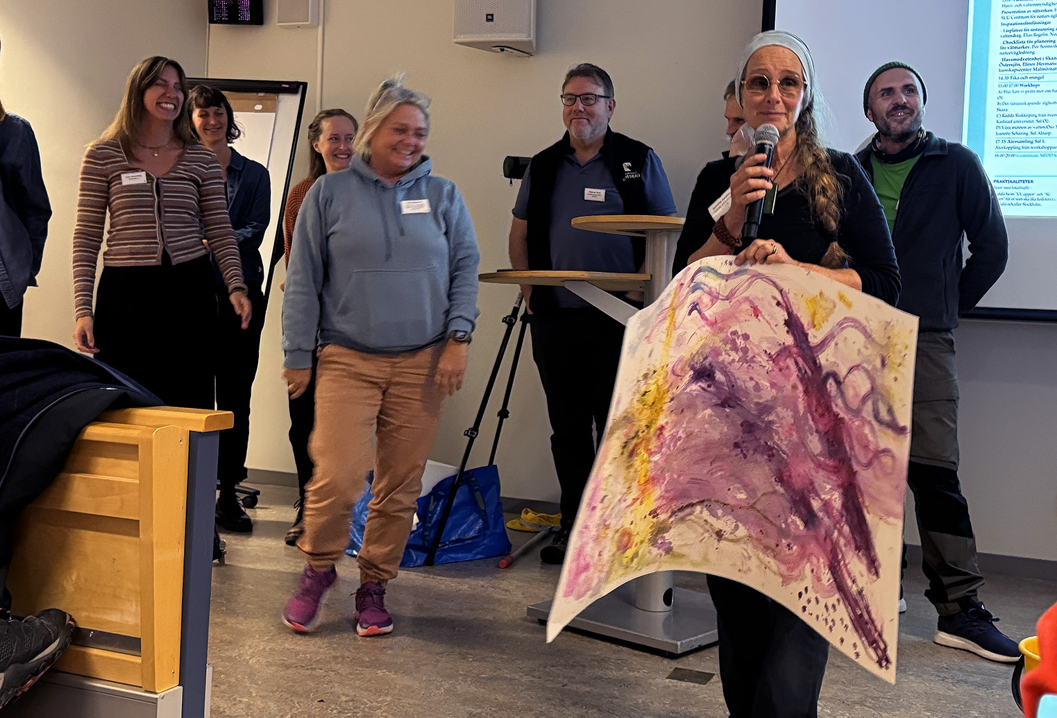 Personer visar upp målningar som de gjort under en workshop. 