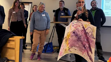 Personer visar upp målningar som de gjort under en workshop.