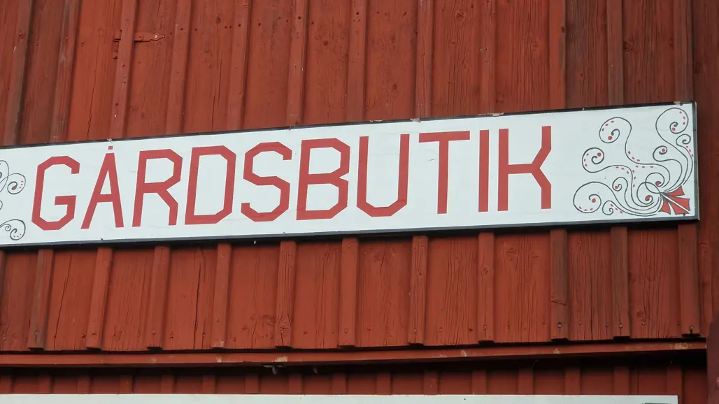 En skylt på en rödmålad vägg som det står Gårdsbutik på