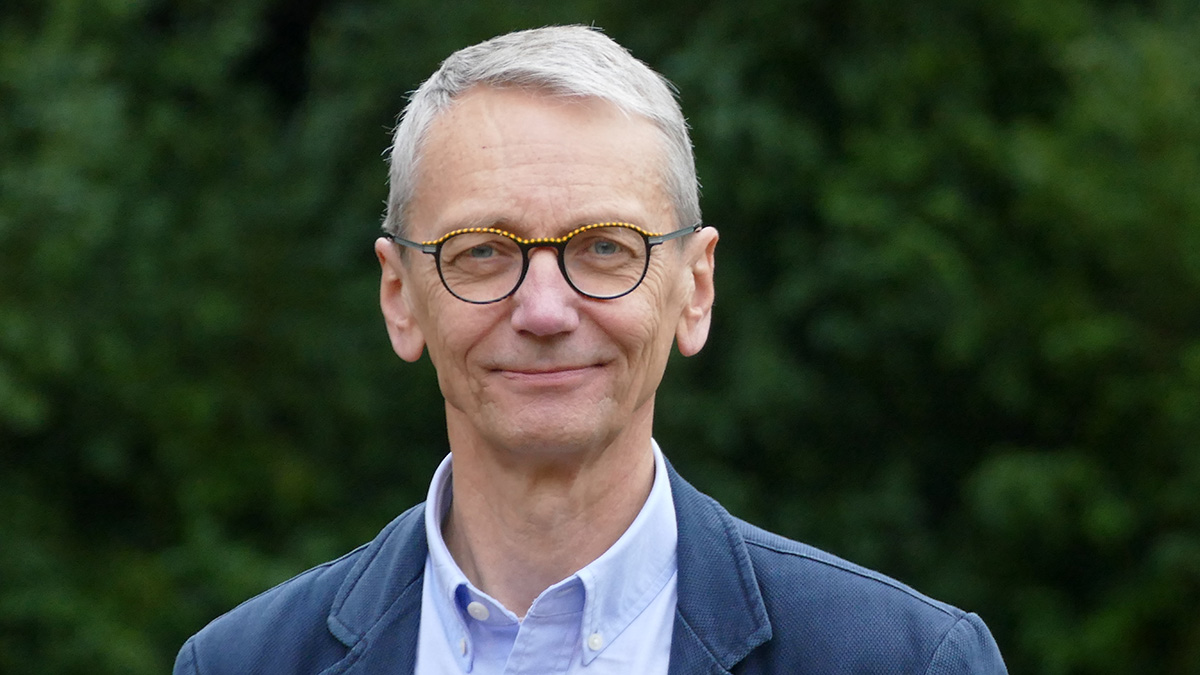 Leende man framför grönska