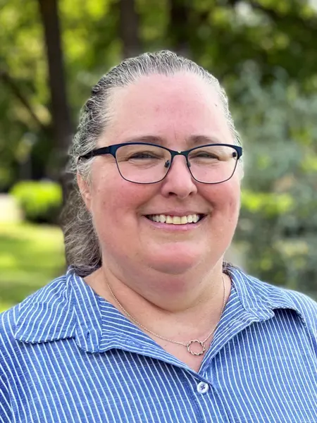 A smiling woman in a blue and white striped shirt. Photo.