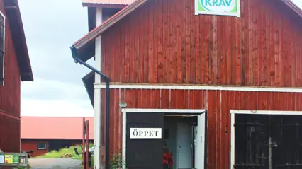 Foto av en röd lada med KRAV:s gröna logotyp på väggen.
