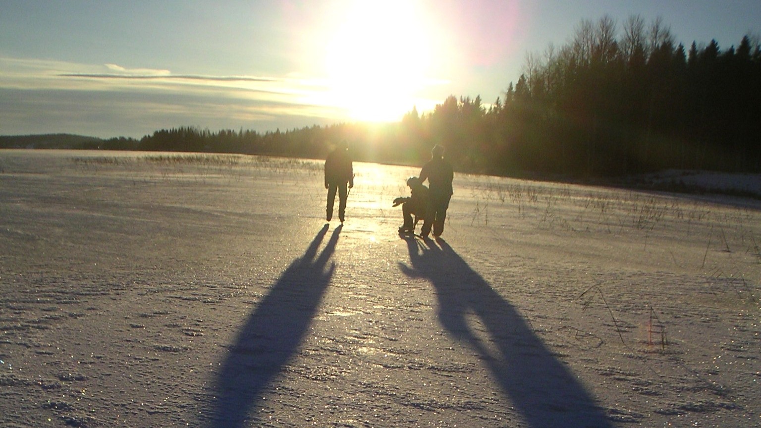Three persons on an ice-coverd lake in the sun