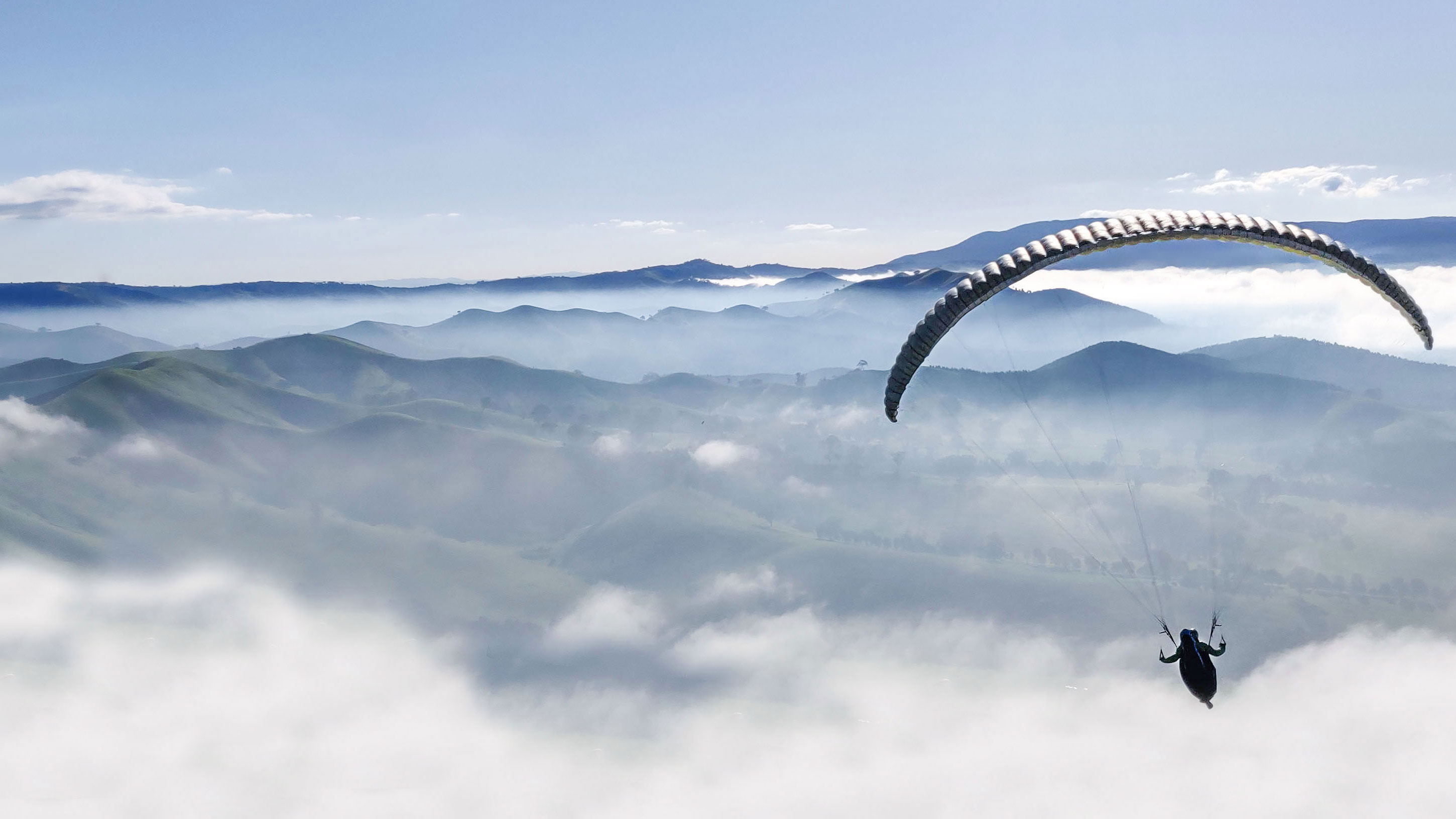 A paraglider over mountains and clouds. Photo: Shutterstock.
