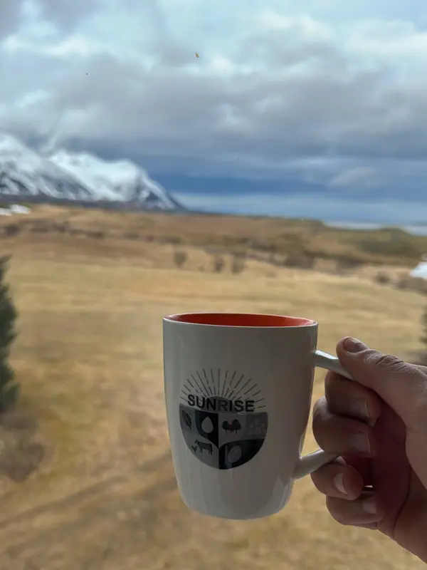 En kaffekopp med SUNRISE logotyp framför ett fjäll. Foto.