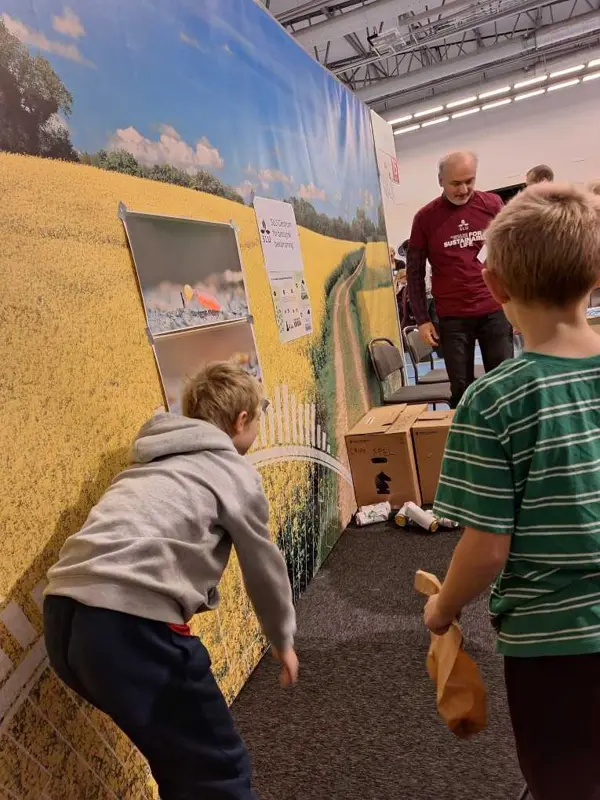 Två barn kastar något på burkar. Foto.