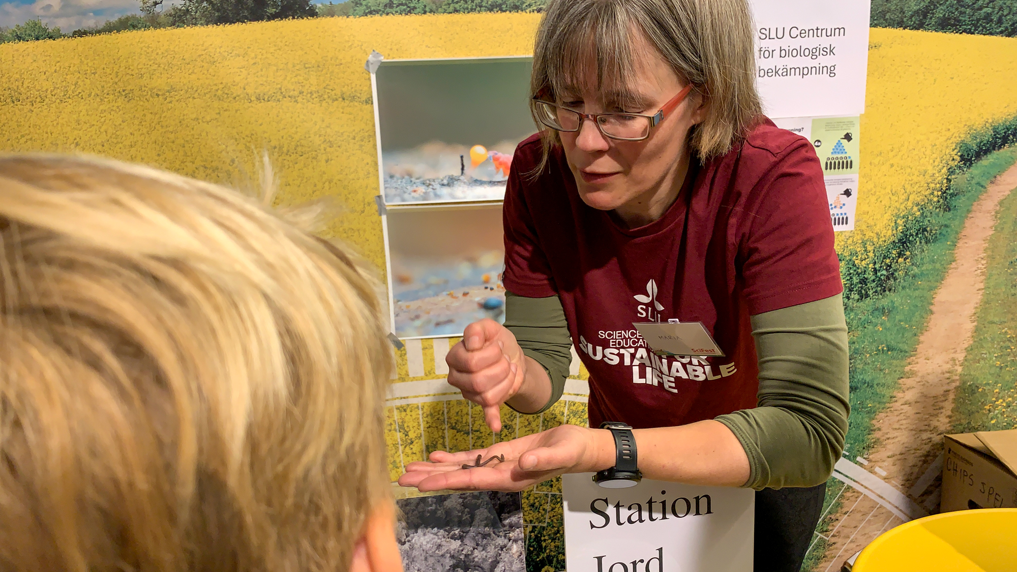 En kvinna visar ett barn en daggmask. Foto.