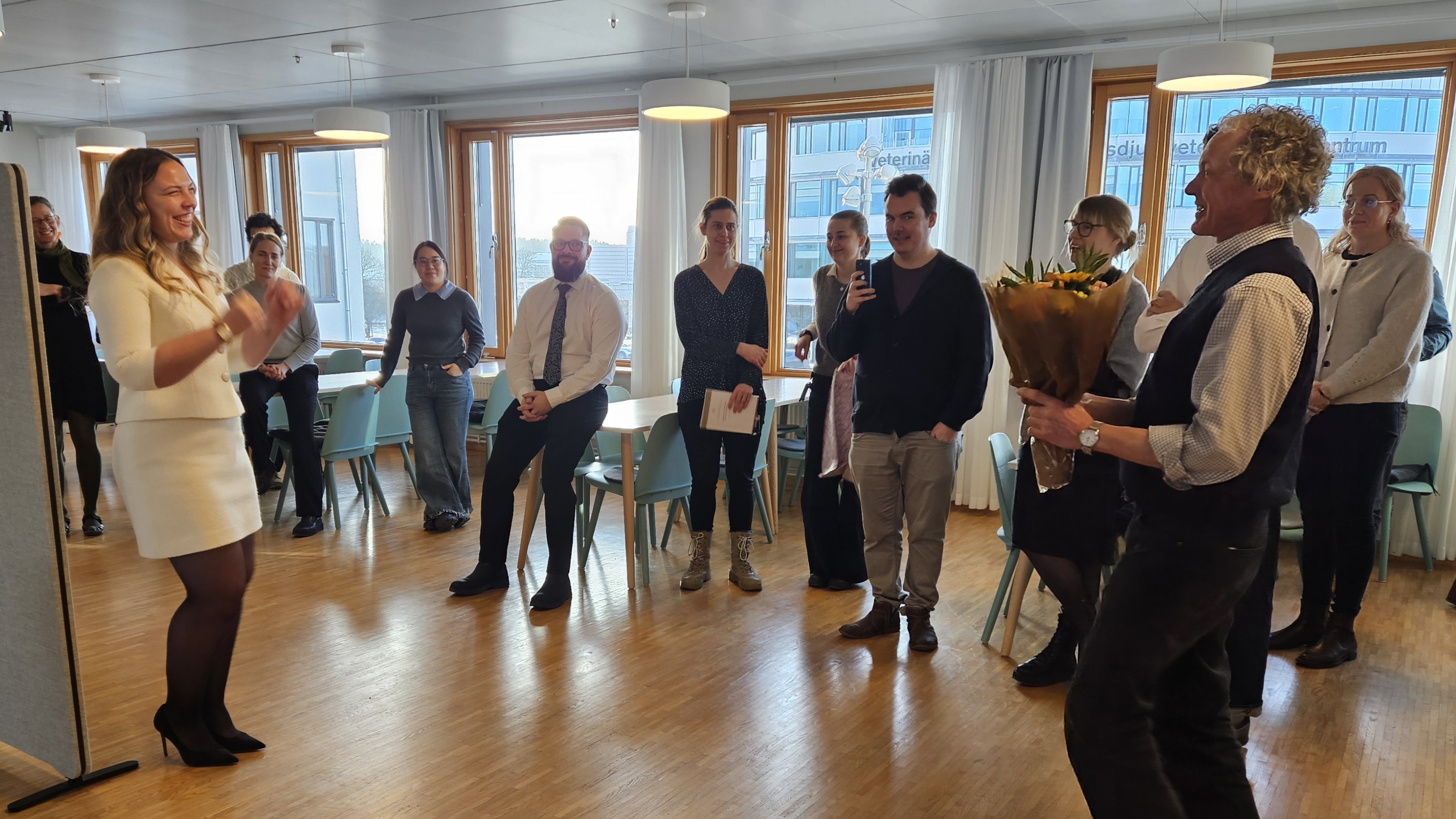 Eleanor Johansson standing ready to receive flowers from the Head of Department.