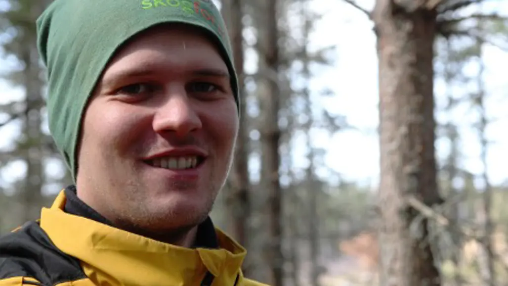 Man med gul mössa i skogen