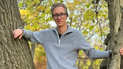 man står lutad mot ett träd