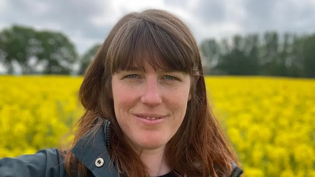 A woman in front of a rapeseed field. Photo.