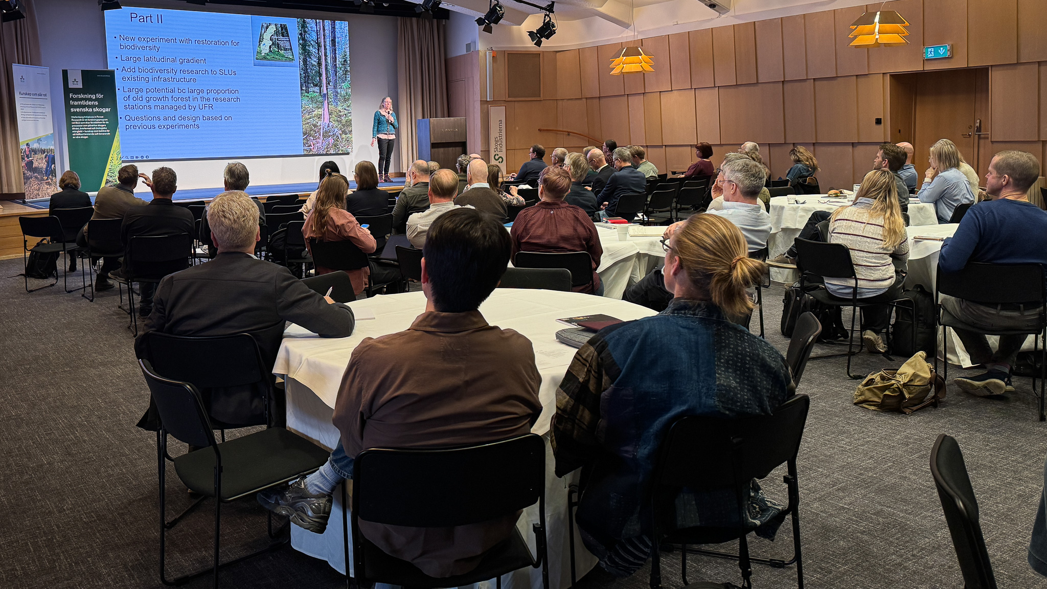 A large group of participants listening to a presentation in a conference room.