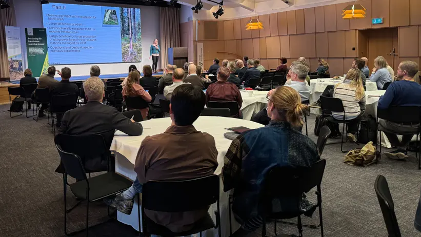 A large group of participants listening to a presentation in a conference room.