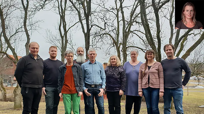 9 människor på rad i en gräsbacke. Foto