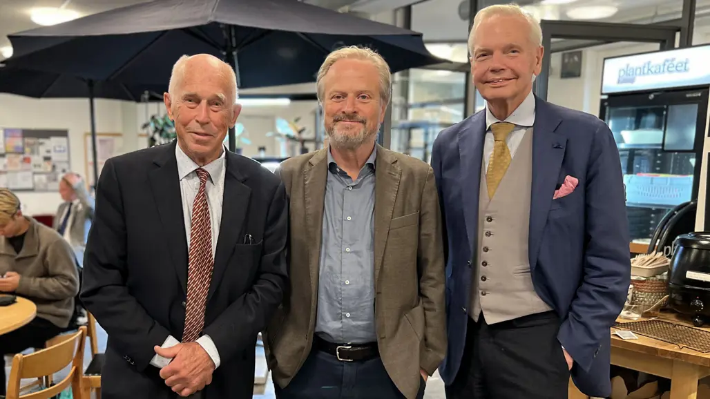 tre män i kostym i ett café