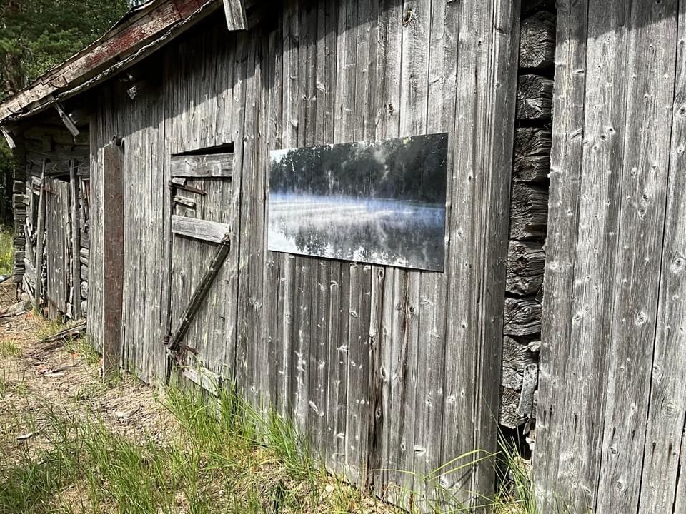 Ett fotografi på en dimhöljd tjärn sitter på en vägg på en gammal lada.