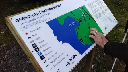 Person läser en taktil karta över Garnuddens naturreservat.