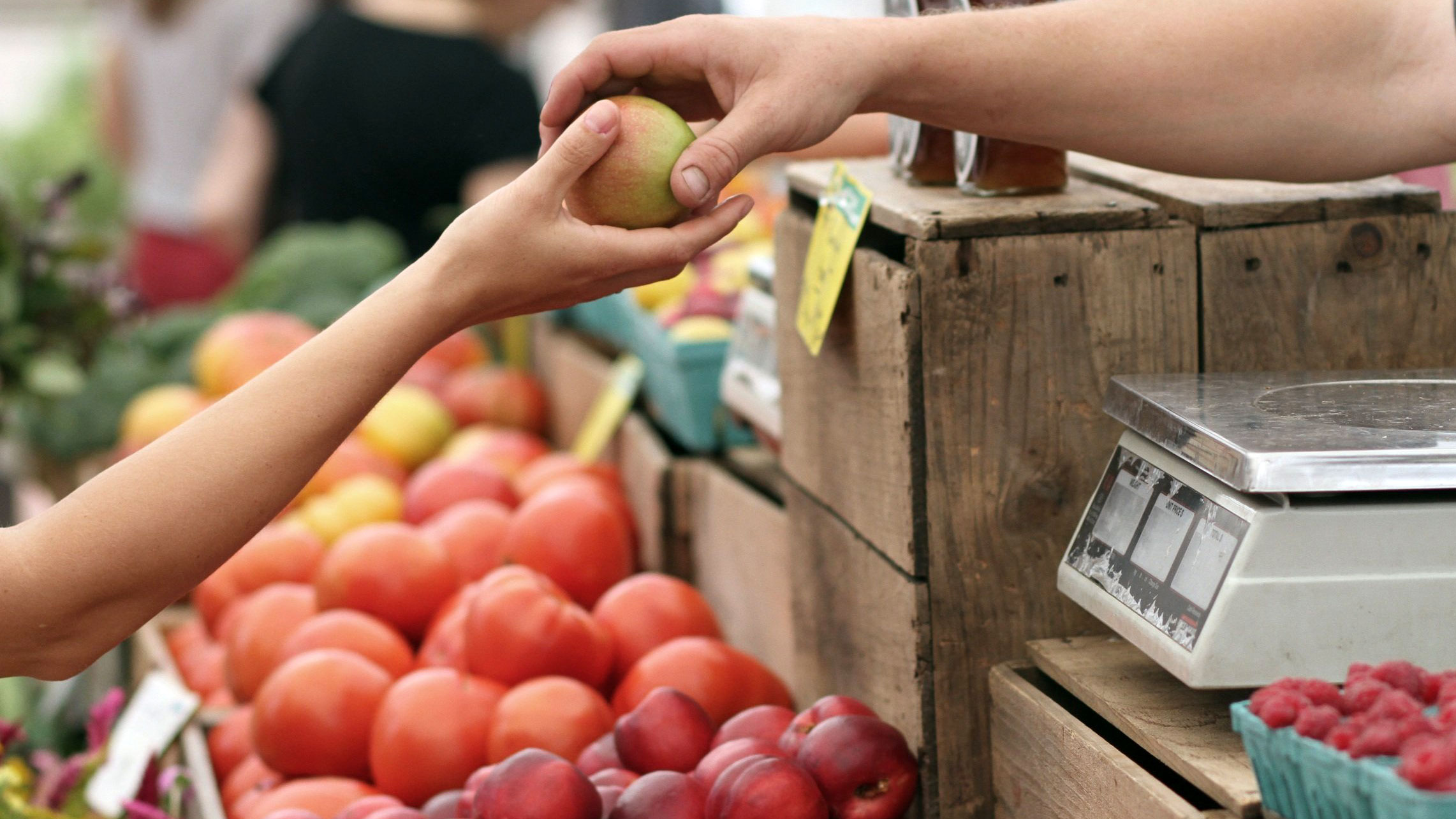 Två händer utbyter ett äpple på en fruktmarknad. Foto: Pixabay